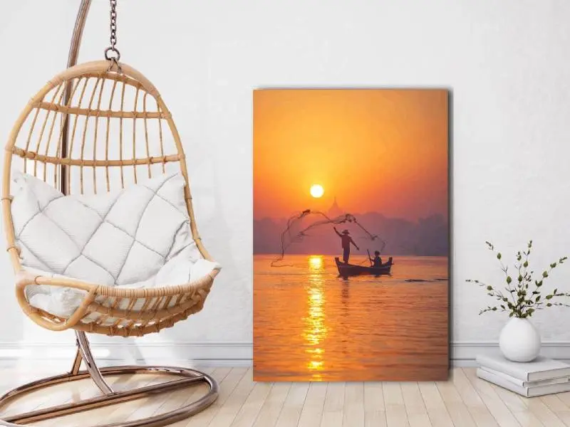 Woonkamer met hangstoel en daarnaast een foto op canvas van een bootje bij zonsondergang