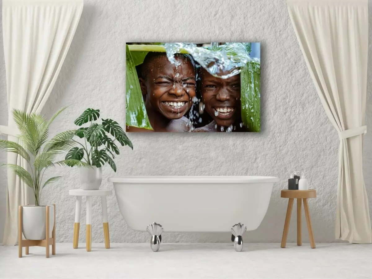 Badkamer met foto op aluminium boven bad van vrolijke Afrikaanse kinderen die schuilen onder een groot blad van een boom