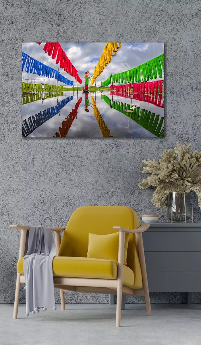 Fotokunst 'Making Fabrics' aan de muur in woonkamer boven gele stoel