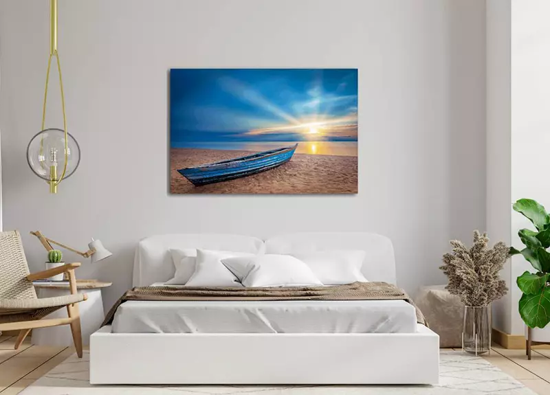 Slaapkamer met foto van bootje bij zonsondergang aan de muur boven bed 